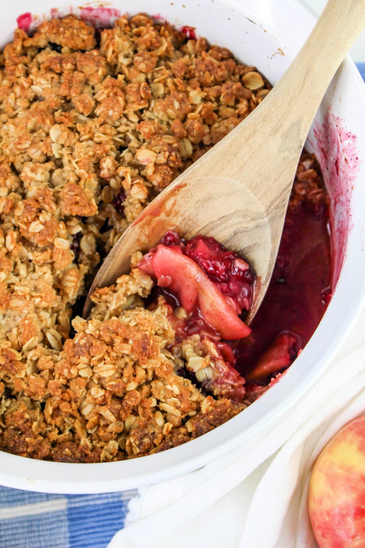 Wooden spoon in a baking dish of Apple Blackberry Crumble.