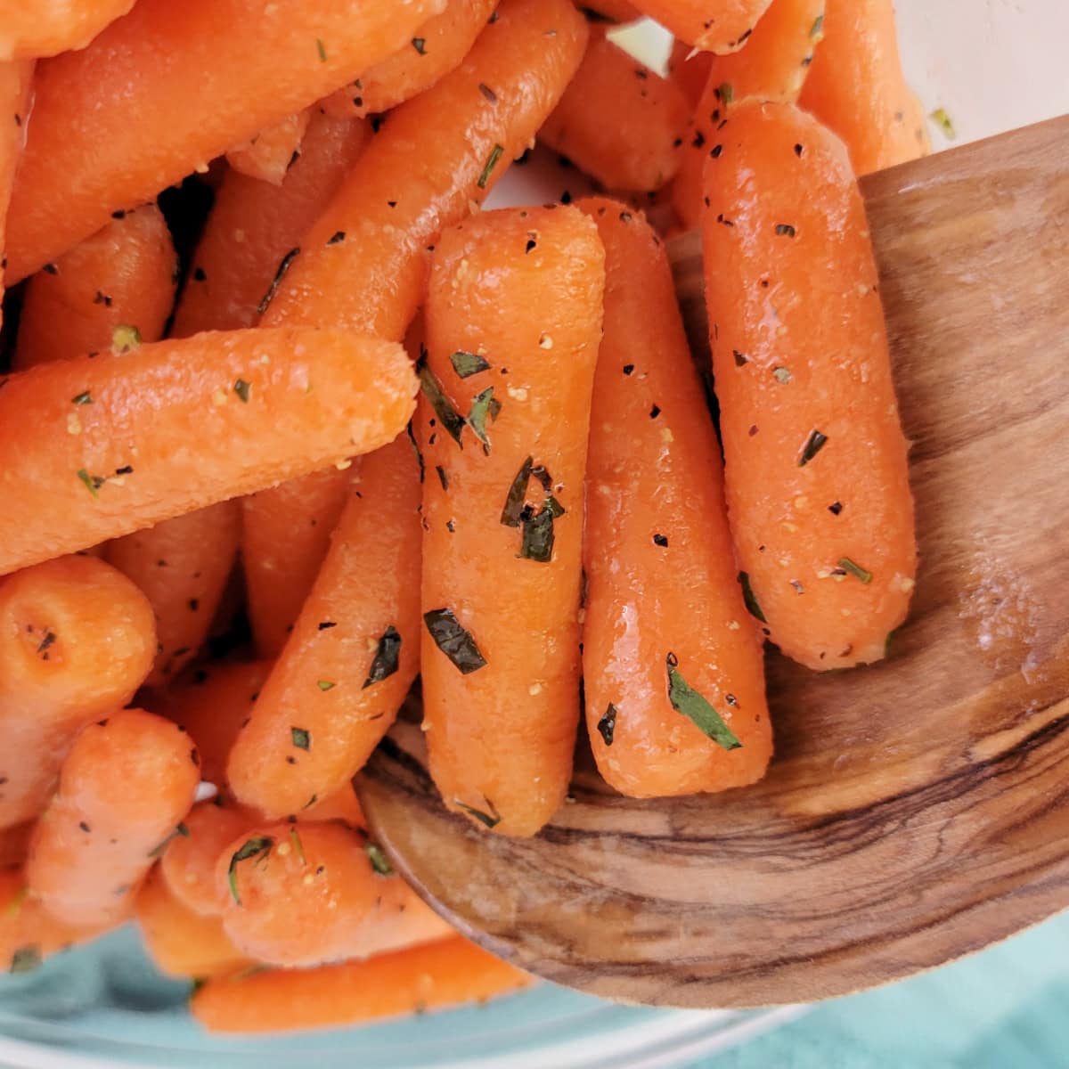 Close up of honey tarragon carrots on a wooden spoon.