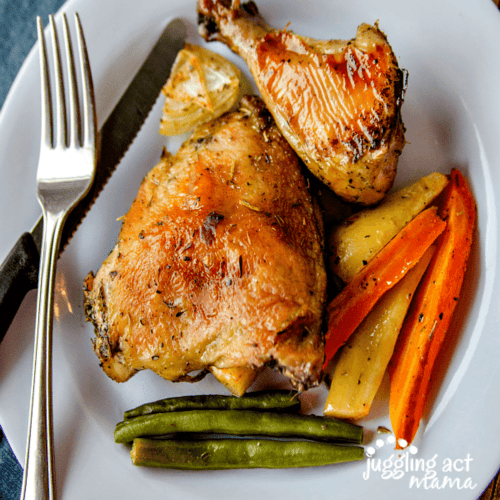 Top down view of roasted chicken with vegetables on a plate.
