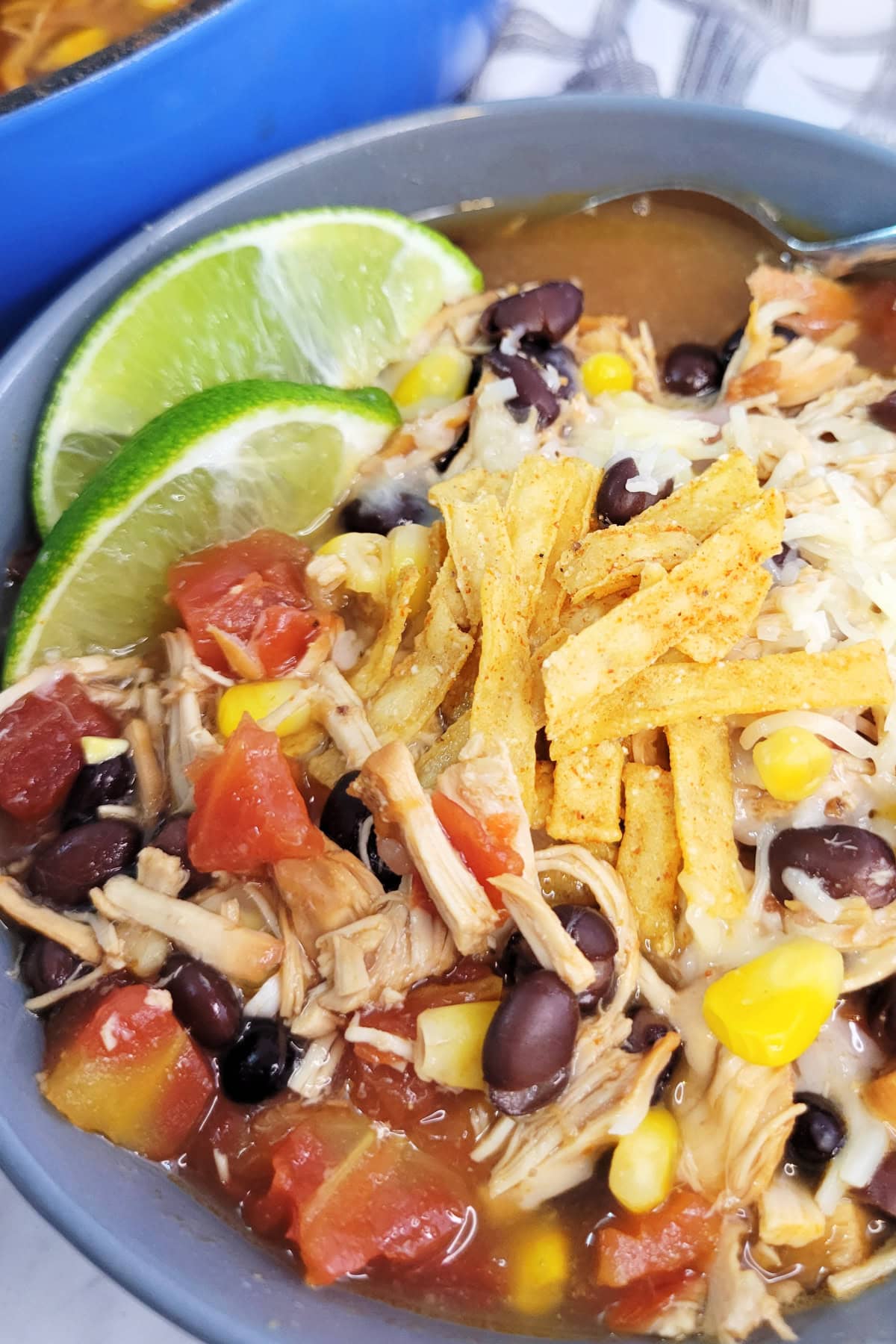 Chicken Southwest Soup Recipe: bowl of soup with tortilla strips and lime wedges.