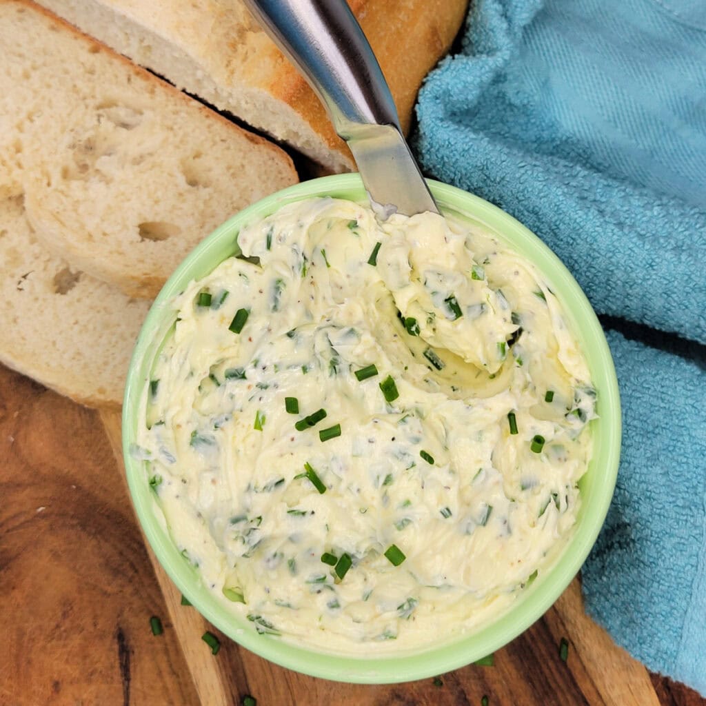 Top down view of Garlic Chive Butter in a bowl with a knife.