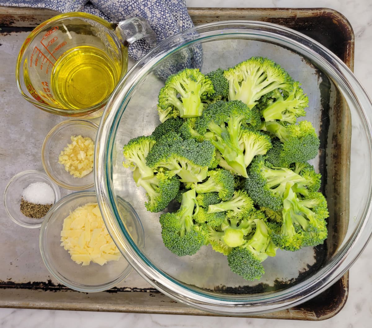 Garlic Parmesan Broccoli ingredients in bowls on a baking tray.