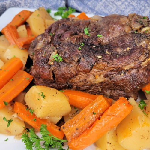 Close up of Italian Roast Beef on a platter with root vegetables.