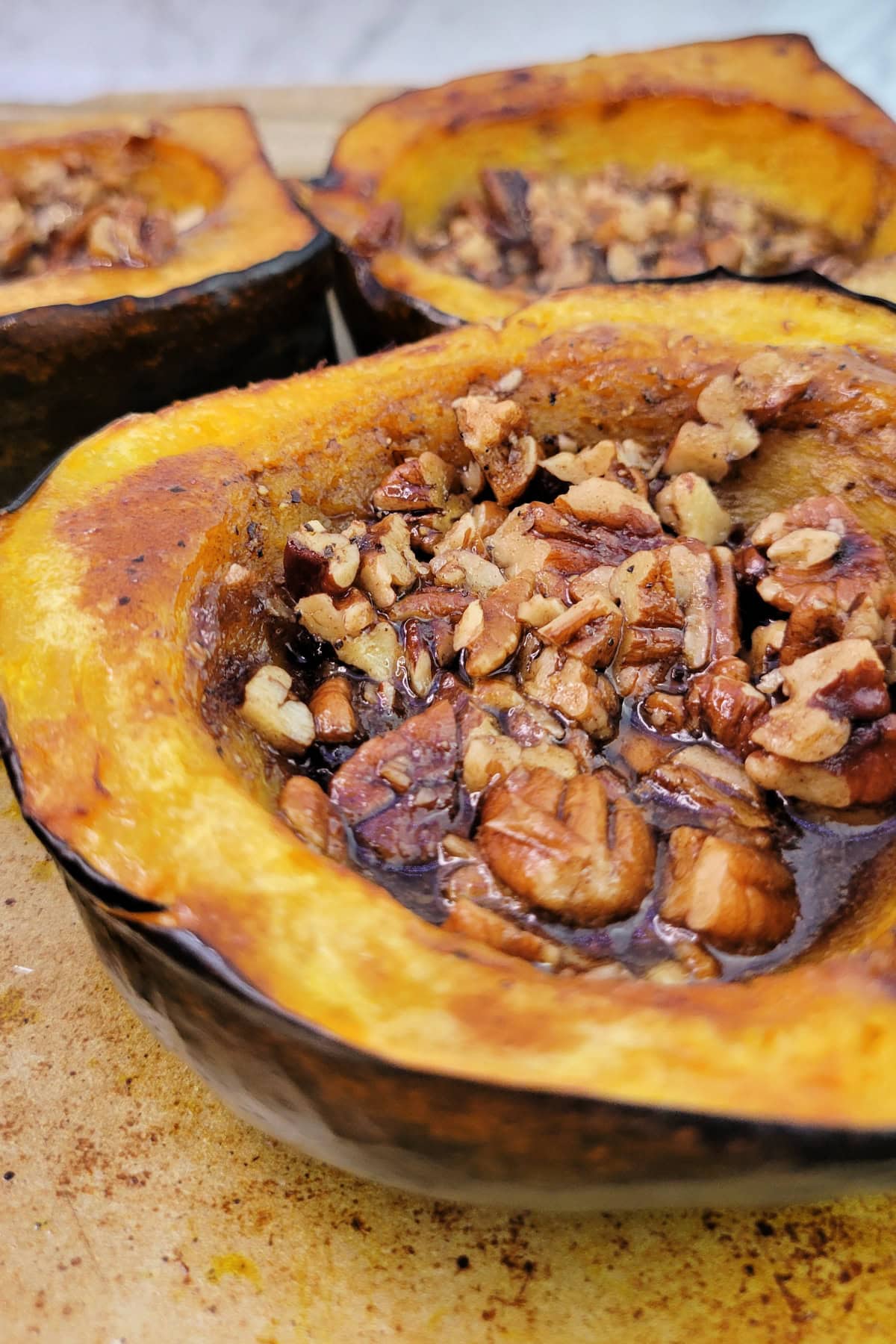 Close up of Brown Sugar Roasted Acorn Squash with pecans and maple syrup.