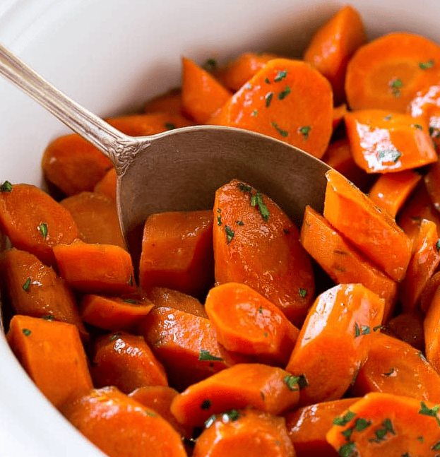 Close up of slow cooker carrots with a spoon.