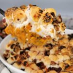 Close up of spoonful of sweet potato casserole with pecans.