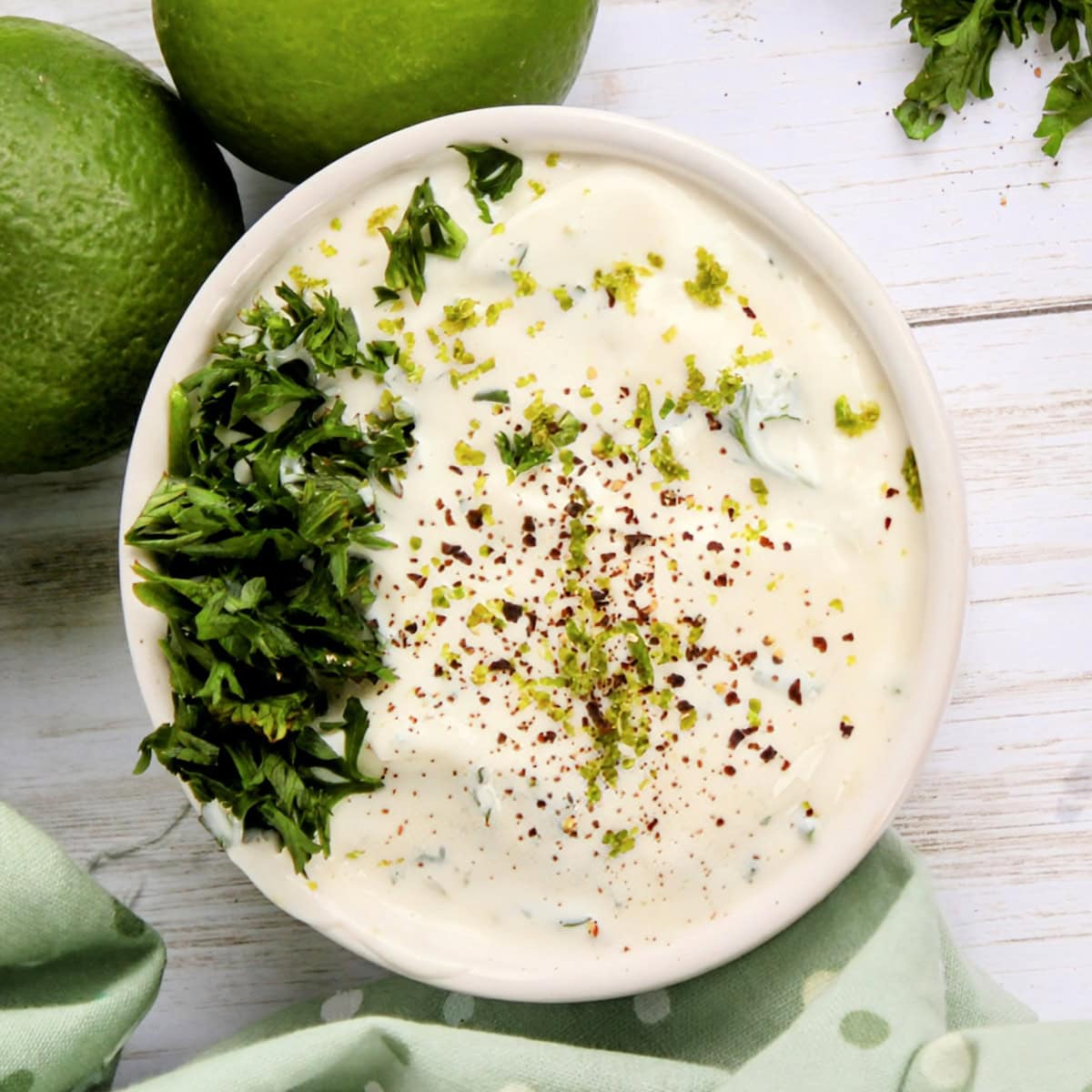 Top down view of lime mayo recipe, garnished with parsley, lime zest, and black pepper.
