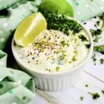 Close up of lime mayonnaise with chopped parsley, lime zest, and black pepper.