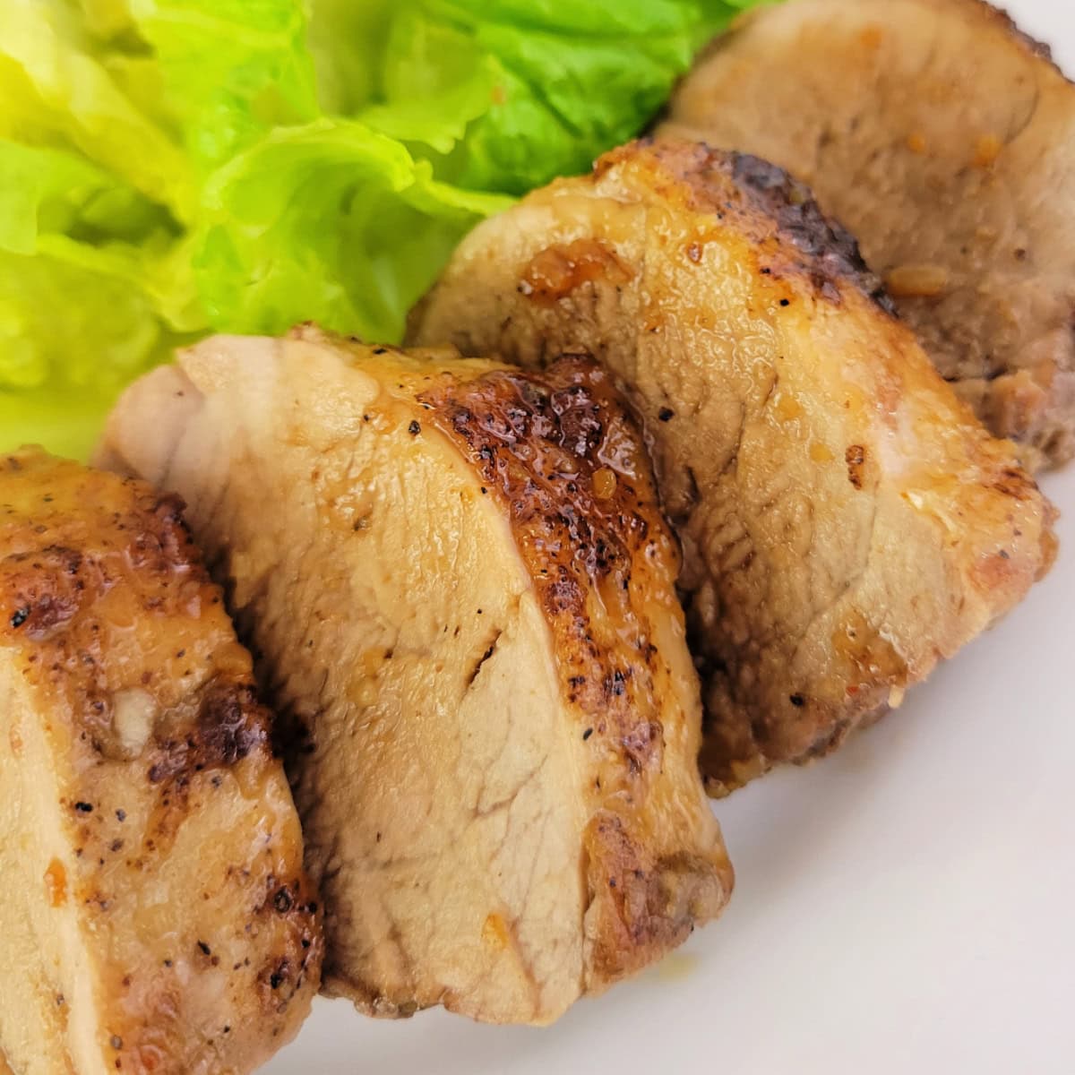 Close up of slices of honey garlic pork tenderloin on a plate.