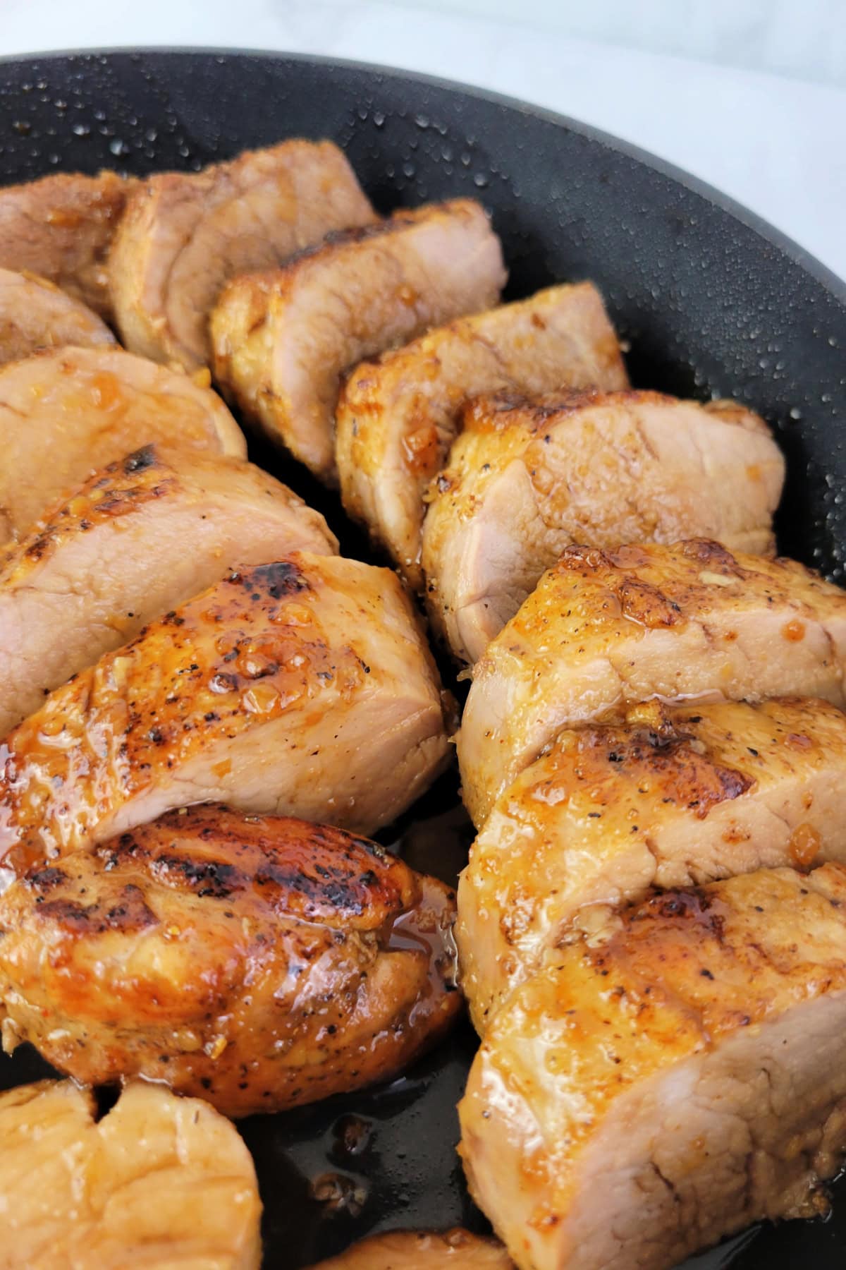 Sliced honey garlic pork tenderloin in a skillet.