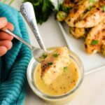 Close up of a fork with chicken dipped into Caesar butter sauce.