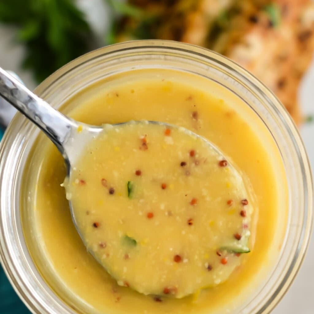 Top down view of Caesar Butter Sauce on a spoon over a jar.