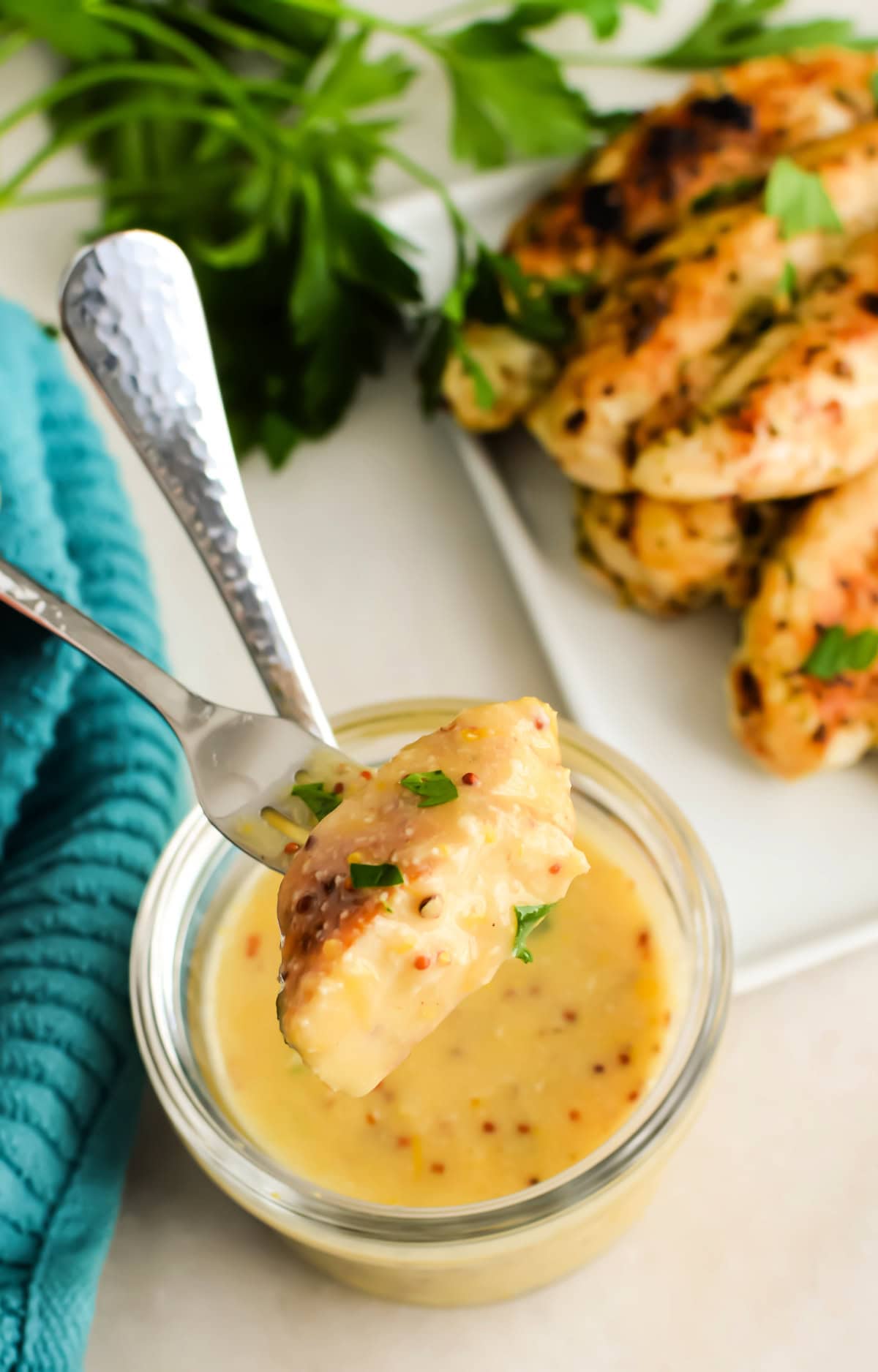 A fork with chicken dipped into Caesar butter sauce.