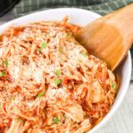 Large bowl of Slow Cooker Chicken Marinara with a wooden spoon.